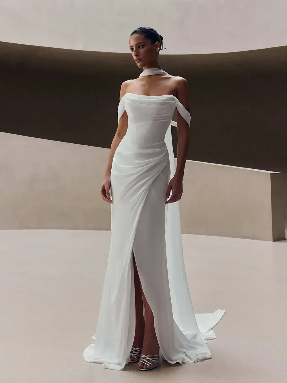 model is wearing a fit and flare off the shoulder bridal gown
