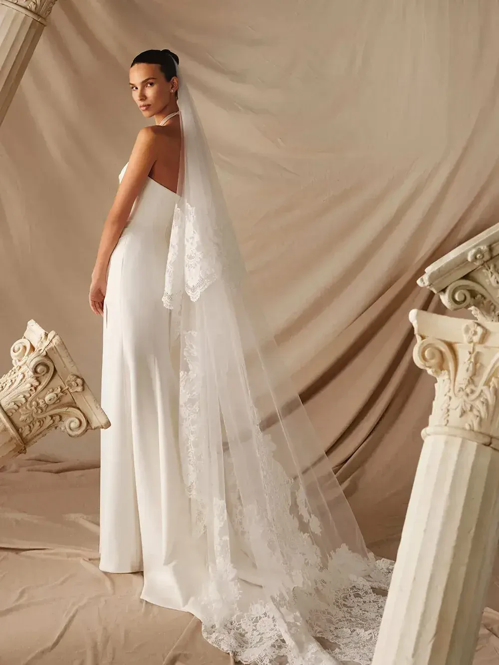 model is wearing a strapless ball gown with a long veil